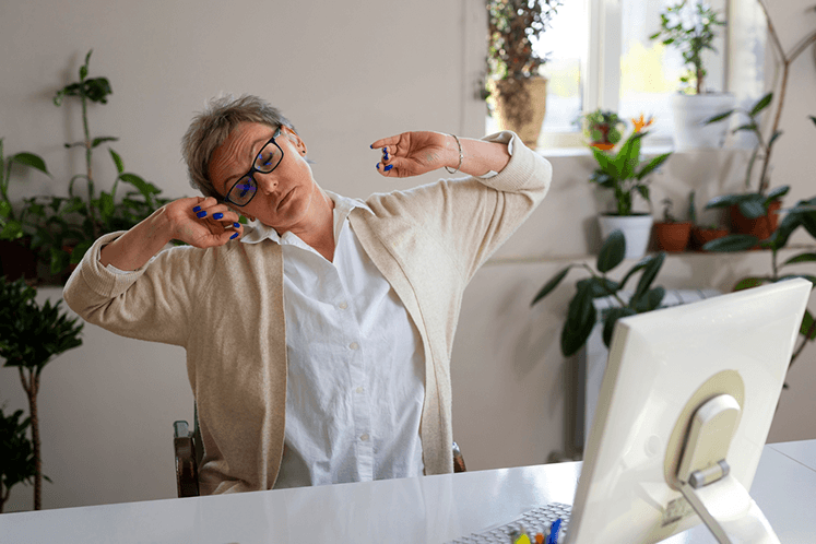 Femme qui s'étire devant son ordinateur, à son bureau
